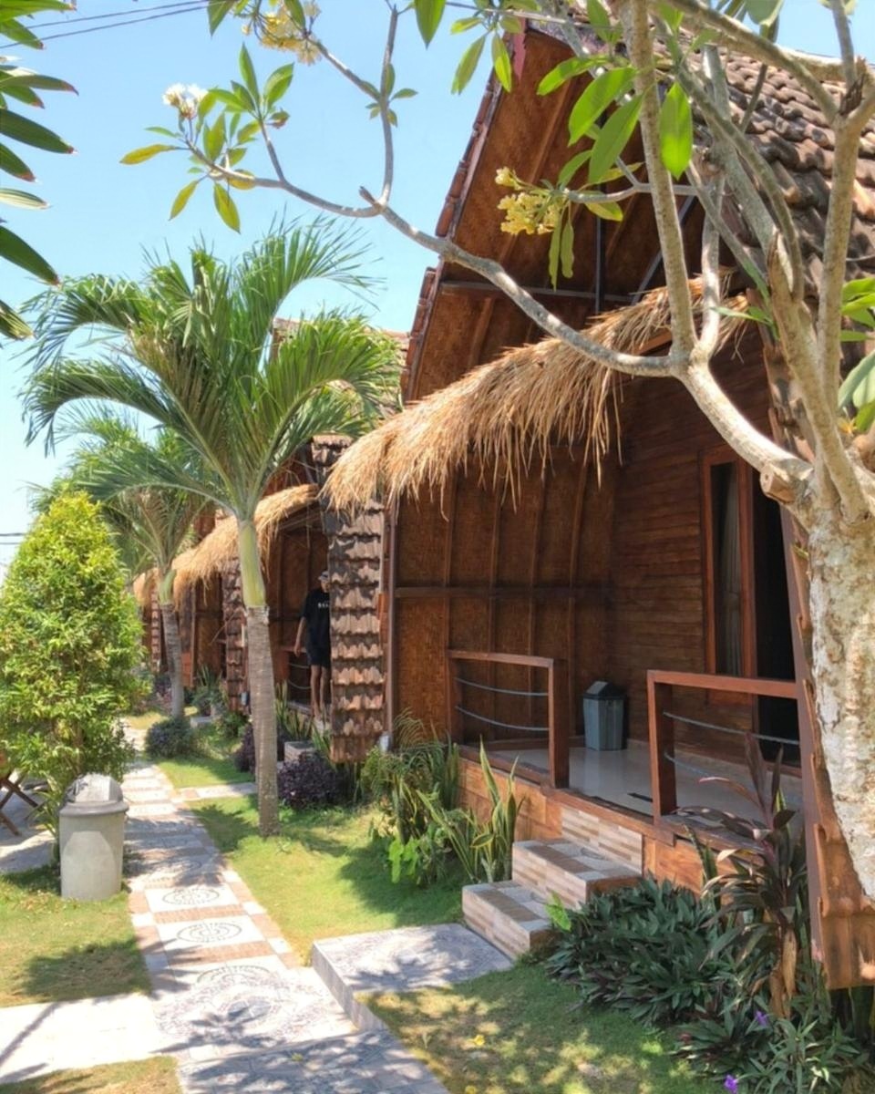 A thatched bungalow in a garden of palms