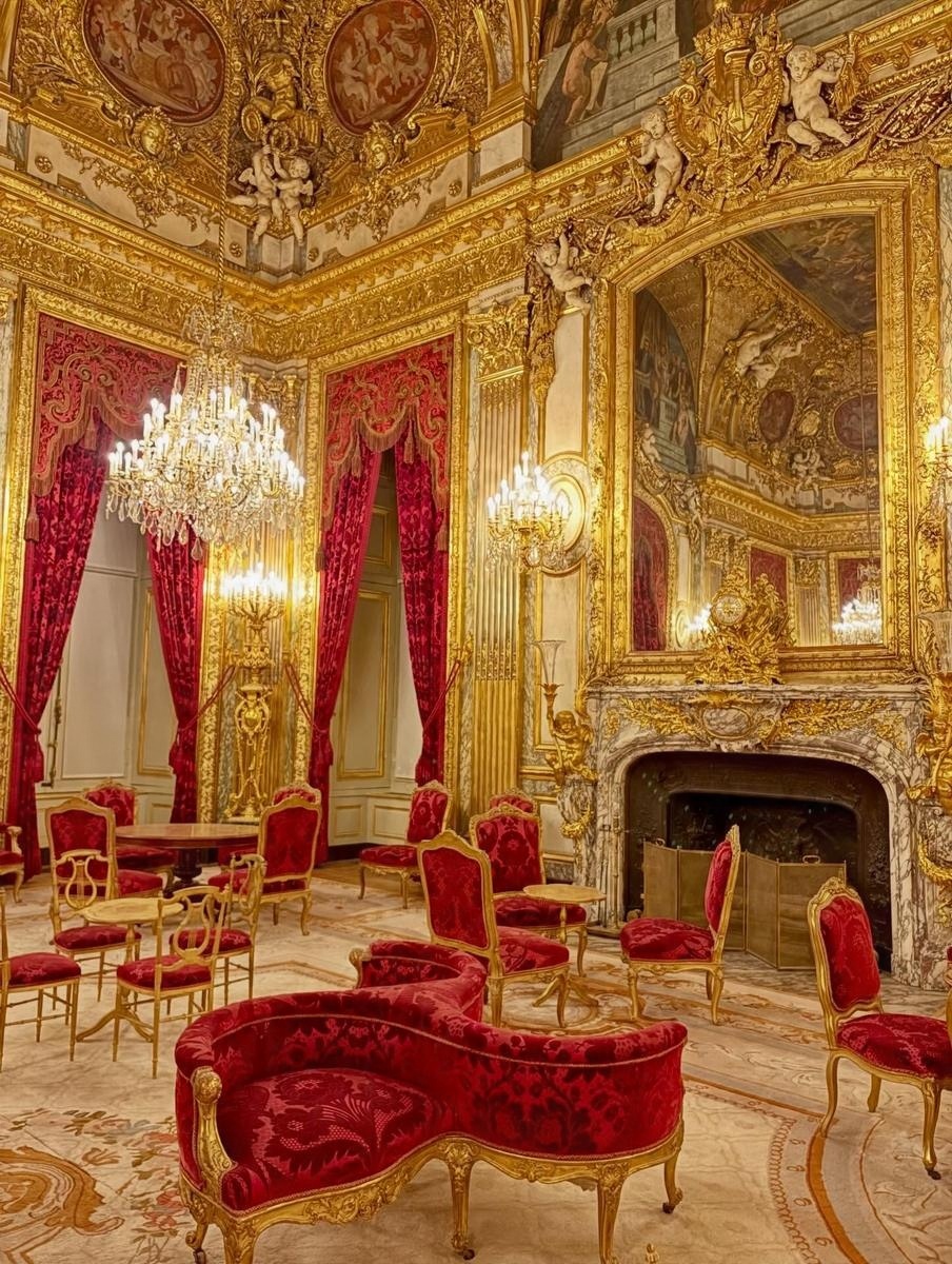 A gilded palace room with red chairs
