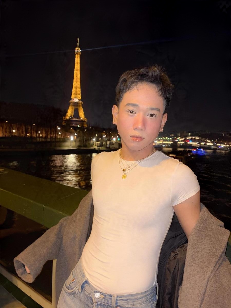 Mr. Bali at night by the river in Paris, the Eiffel Tower behind him